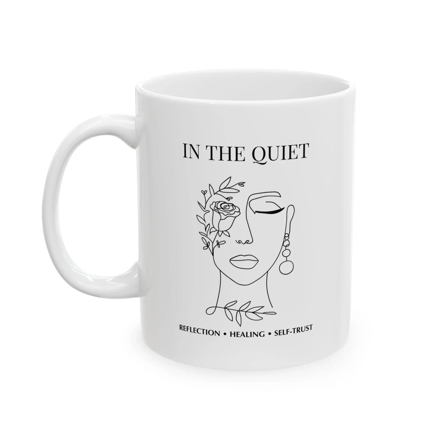 White ceramic mug featuring “In The Quiet” text and minimalist floral face illustration on a clean white background.