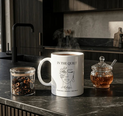 Minimalist kitchen scene featuring a white “In The Quiet” mug with herbal tea, loose tea leaves, and honey jar, creating a calm self-care and reflection aesthetic